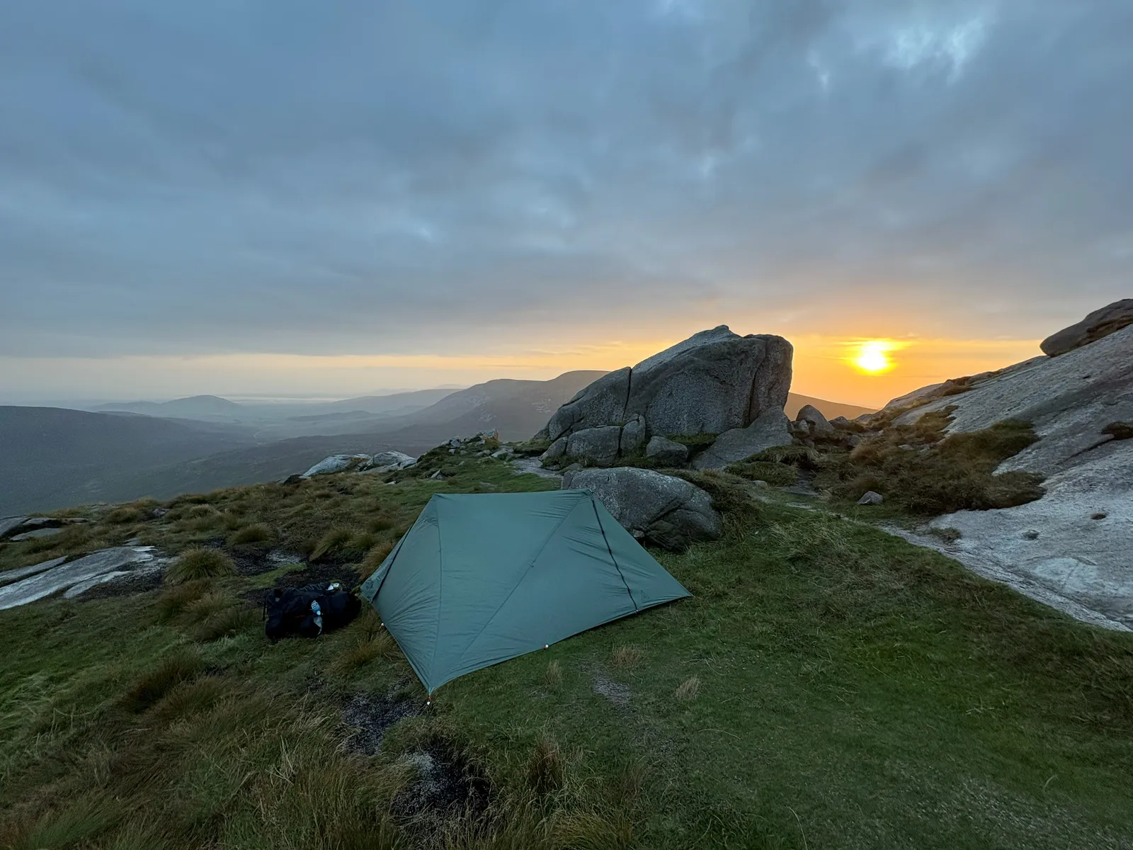 The Durston X-Mid 2 at golden hour beside a granite tor as the sun sets over the Mourne Mountains — the calm before the storm